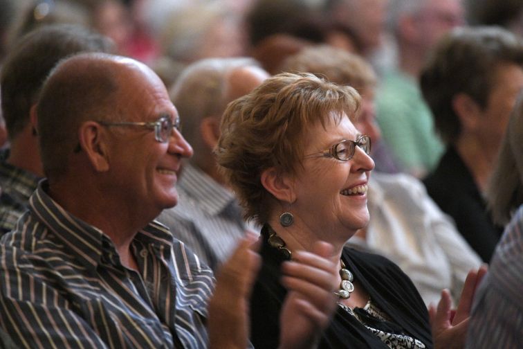 Fits of laughter from man and woman in audience as they watch Seniors Comedy Show on stage