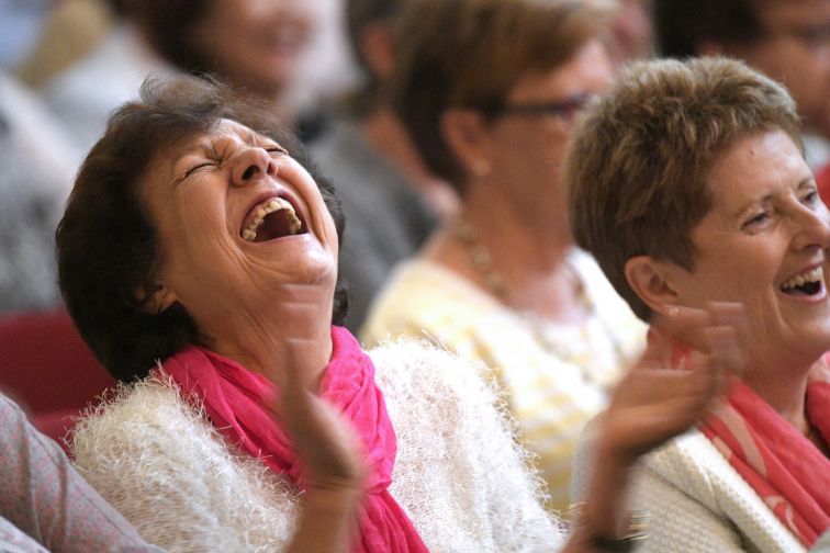 Woman throws back her head, laughing so hard at the jokes at Seniors Festival Comedy Show