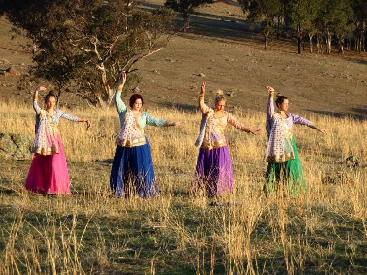 Women dancing in field.