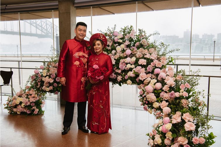 A couple pose next to a floral garland inside the Sydney Opera House