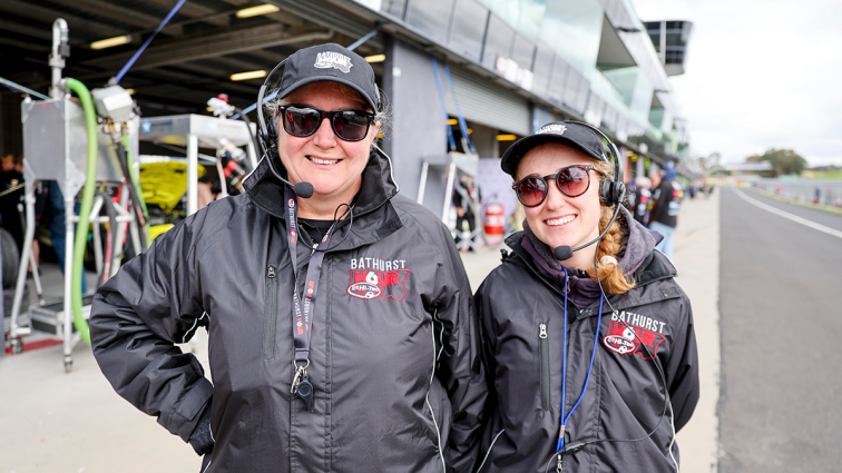 two volunteers smiling at a race track