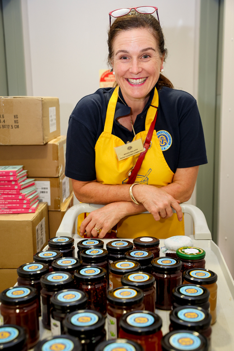 smiling volunteer standing behind a tray of jarred goods