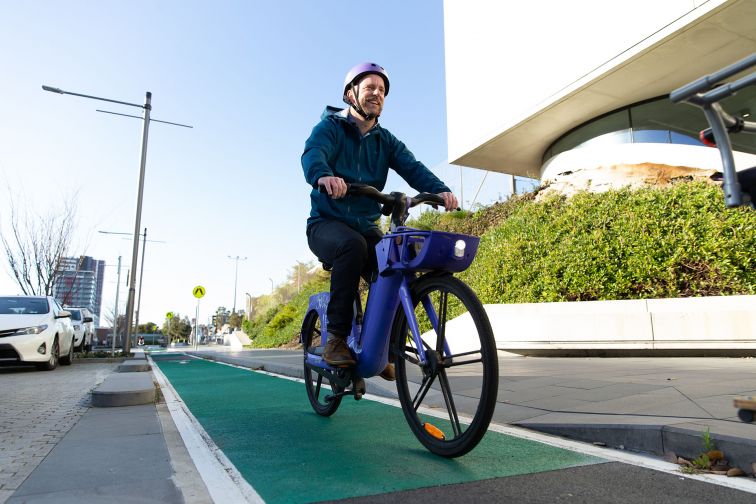 A man wearing a helmet rides a bike down a bike lane on a street.