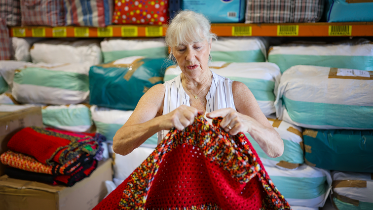 older female volunteer crocheting a blanket