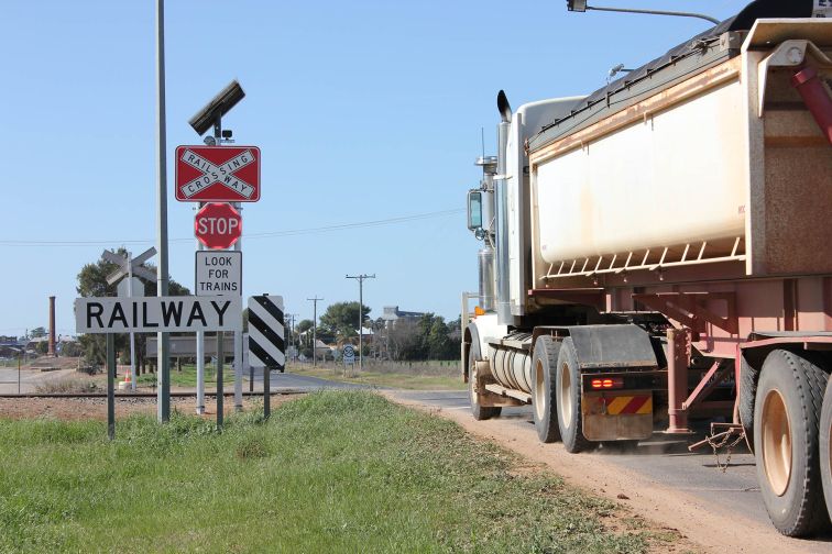 A truck crosses the railway tracks at a level crossing in Narromine, with smart signgage with flashing LED lights installed.