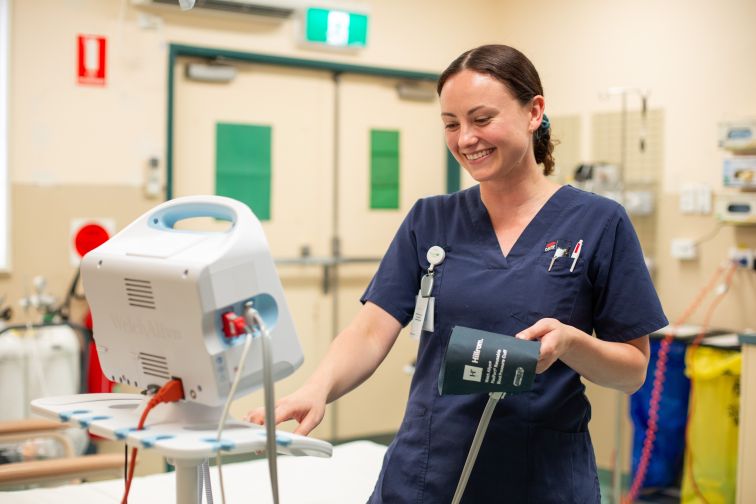 A nurse at Goodooga examines a machine in a hospital ward