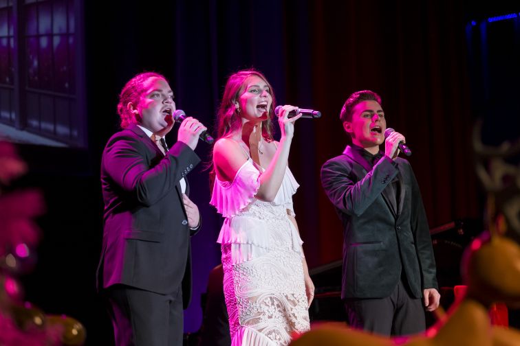 Arlo Sim, Liz Player and Will Skarpona singing on stage