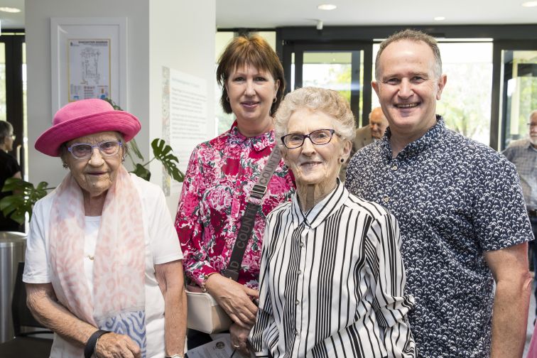 Four elderly people smiling to camera in a foyer