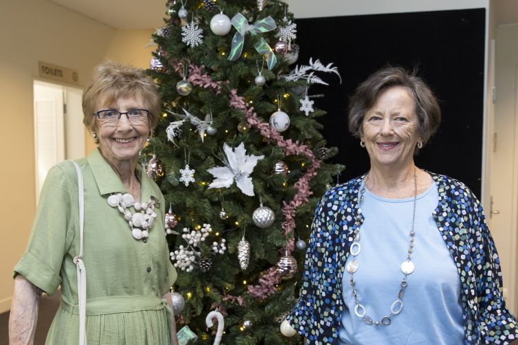 two elderly seniors smiling in front of a Christmas tree