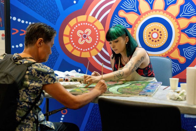 Senior and Indigenous artist adding to canvas painting