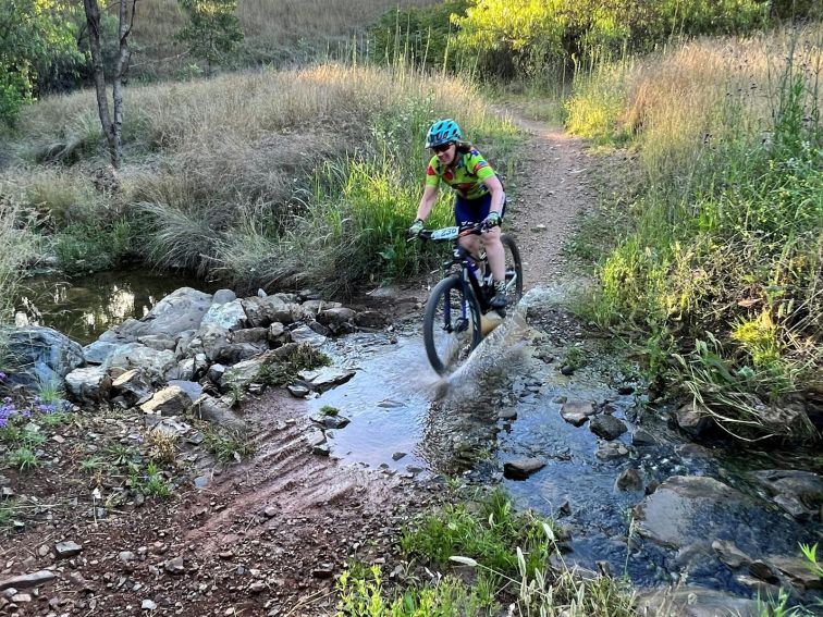 Photo of mountain bike rider crossing through a small river