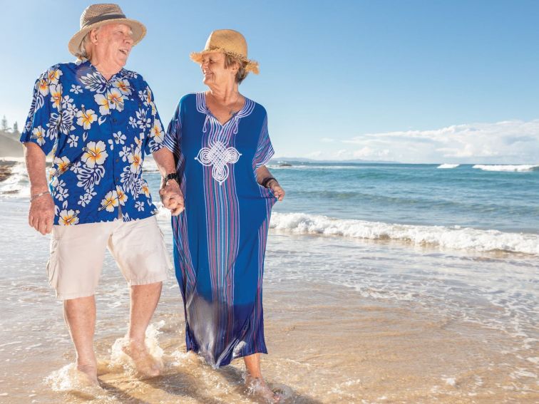 Happy seniors hand-in-hand walking along Shelly Beach