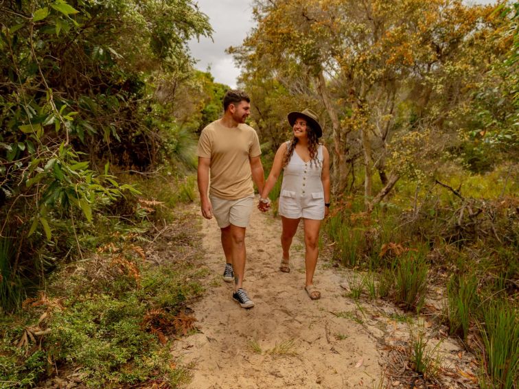 A lady and a man walking through the bush on a path