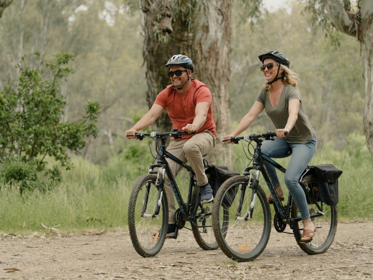 Couple riding bikes through bush scenerey along side the Murray River in Howlong