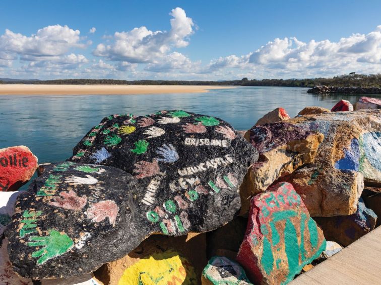 Looking up the Nambucca River esturary, colourful painted rocks in the foreground