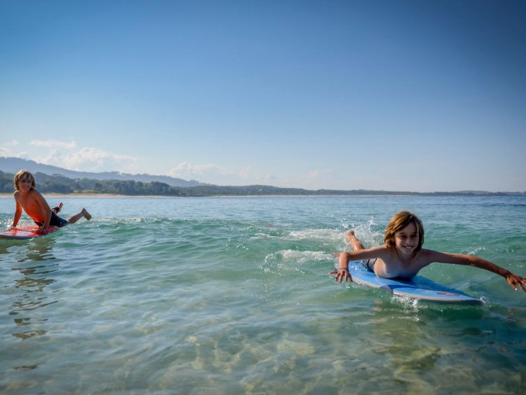 Two boys play on their boards in crystal clear water.