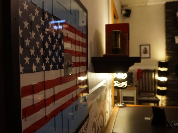 A view of an American flag, a desk, bookshelf and lights