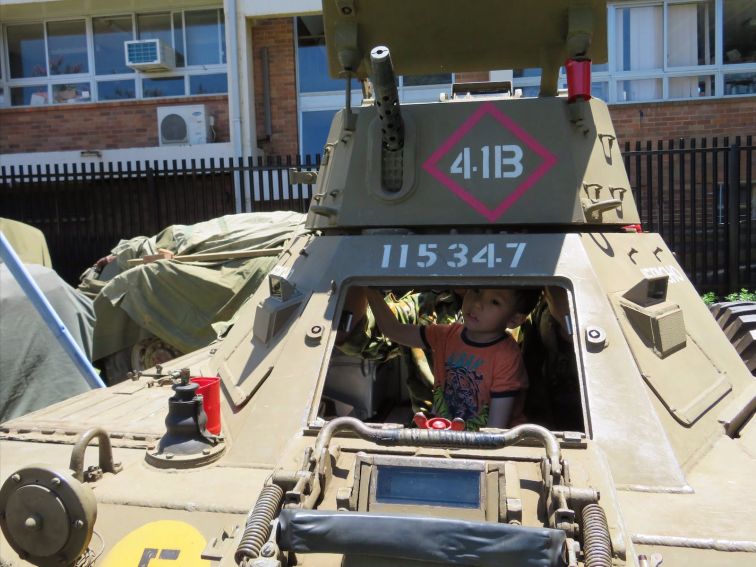 A young visitor looking out from the drivers' seat of a Ferret Scout Car