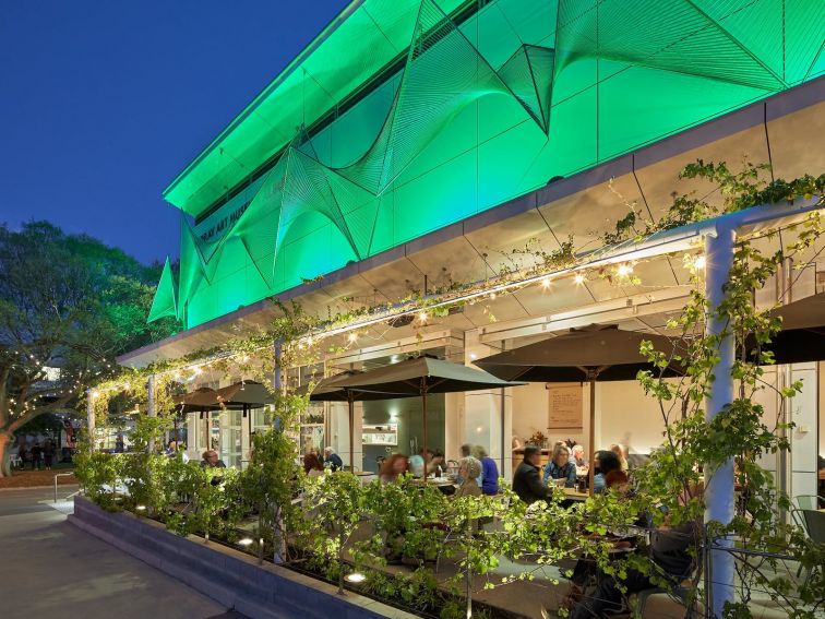 terraced restaurant with vines growing over the al fresco area back lit by green lighting