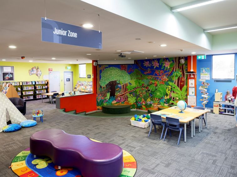A spacious Junior Zone for kids, with furniture, books and a colourful wall mural.