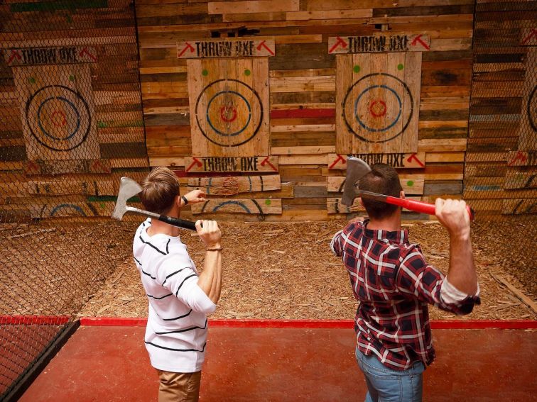 Two guys throwing axes at targets