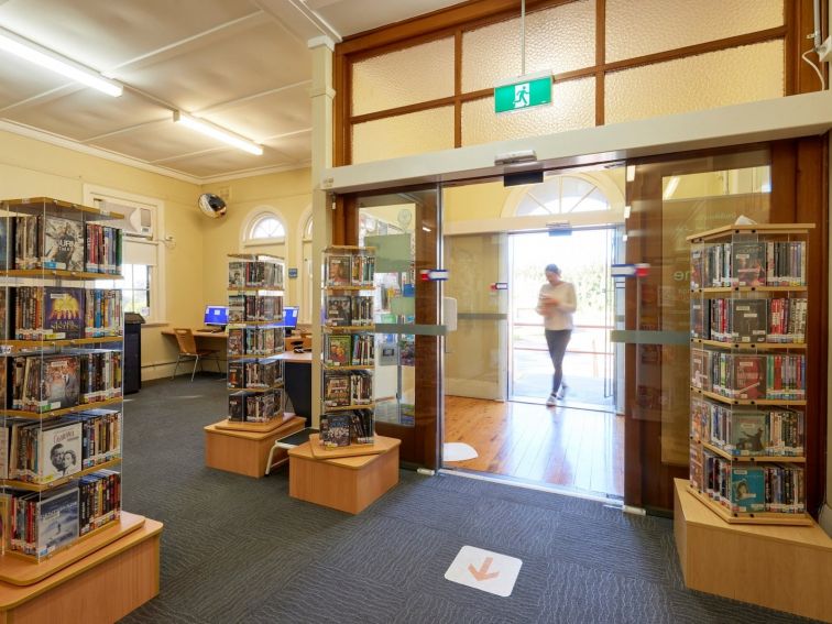 A person walks through the automatic front entry doors into a library.