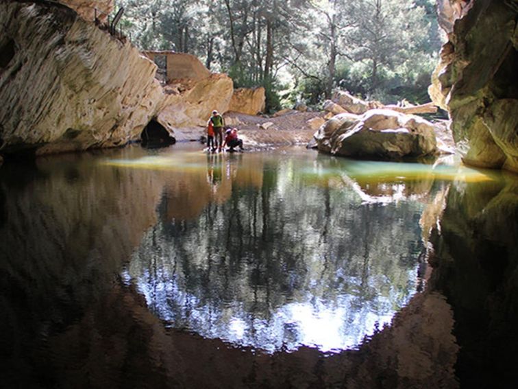 A family beside a pool of water at the entrance to Archway Cave, Abercrombie Karst Conservation