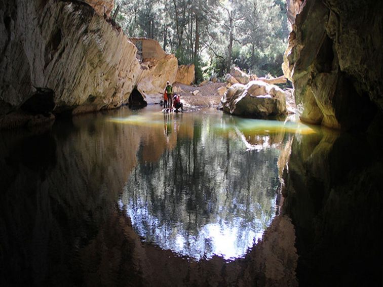 A family beside a pool of water at the entrance to Archway Cave, Abercrombie Karst Conservation
