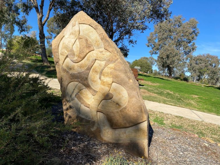 sculpture with snake showing and walking path in background