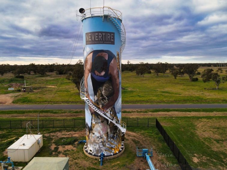A mural on a water tower featuring a shearer and the town name 'Nevertire'.