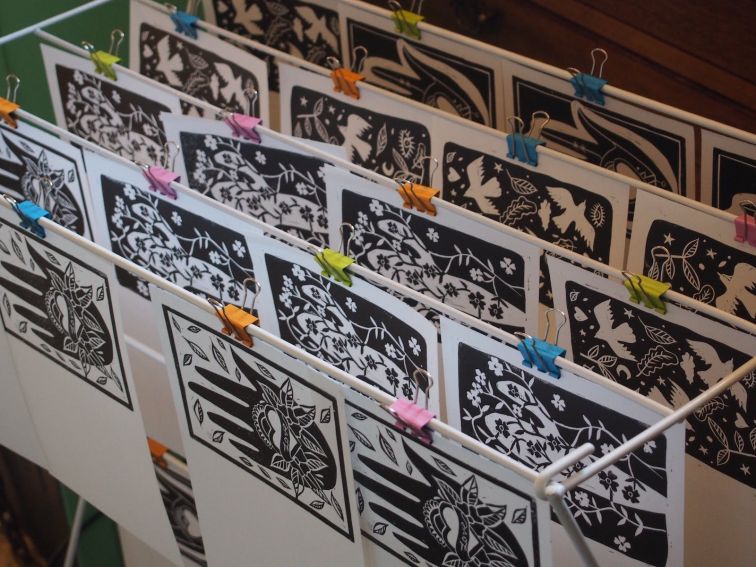 Various block prints drying on a rack