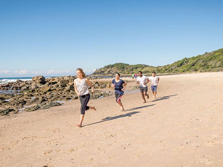 A group of people exercising on the beach along the Port Macquarie coastal walk in Sea Acres