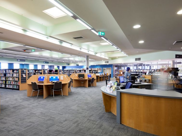 Library interior showing service desk, computer workstations and book shelves