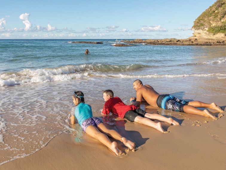 Dad and kids lying on the sand after a swim