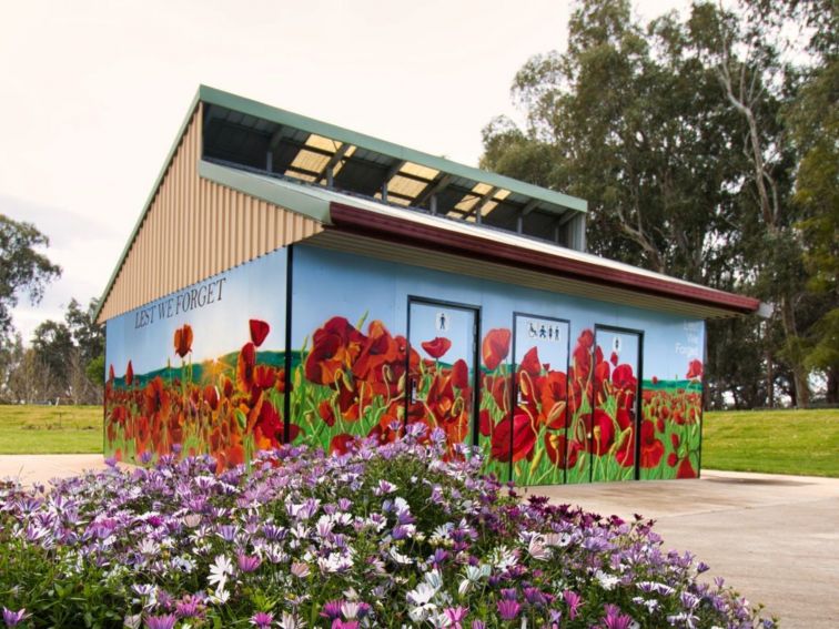 A mural wrapping around a toilet block featuring red poppies on the horizon.