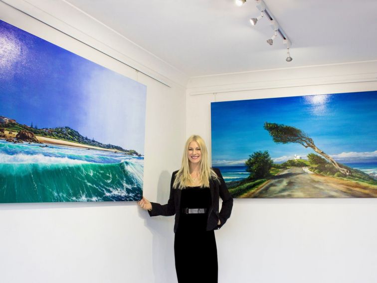 Artist in gallery beside oil paintings