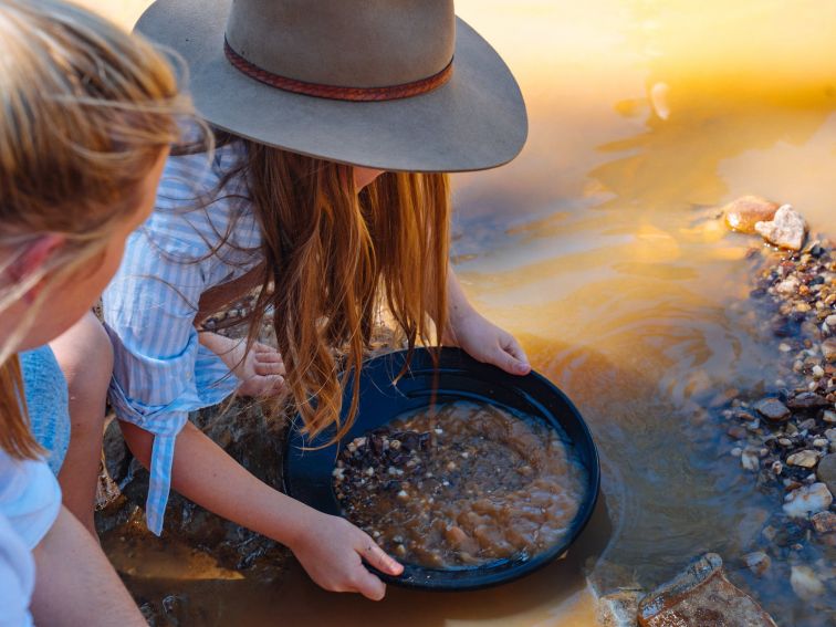 Girl panning out dirt to find gold.