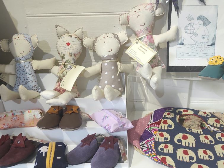 Display of locally made baby items- leather booties, bibs, dolls and print of small girl and bird