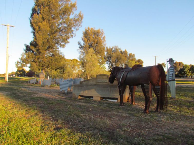 A scrap metal horse stands at a trough, surrounded by sheep and drover sculptures.