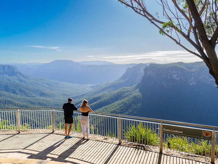 Two visitors looking out at the view of Grose Valley from Evans lookout in Blue Mountains National