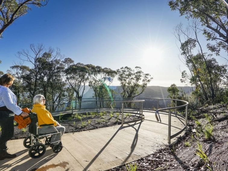 2 visitors heading down the accessible ramp towards Evans lookout in Blue Mountains National Park.
