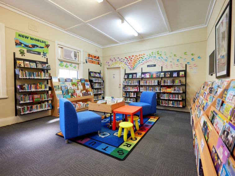Childrens chairs and tables, with shelves full of colourful picture books.