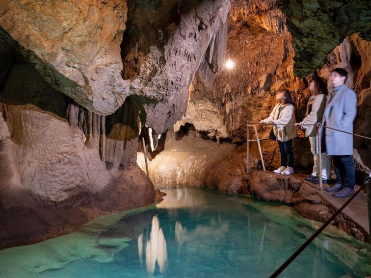 A group of visitors admire a pool of water in a limestone cave at Jenolan Caves. Photo: Jenolan