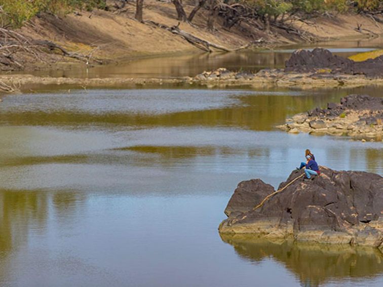 A couple sit on rocks beside the Darling River, Toorale National Park. Photo: Joshua Smith/OEH.