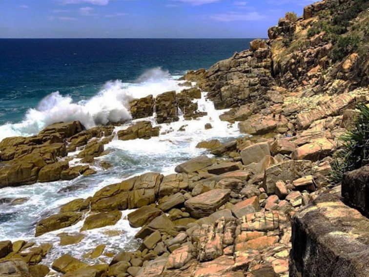 Large swell crashing over rocks and into Mermaid Pools in Arakoon National Park. Image credit: Shane