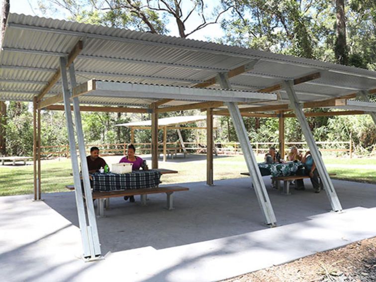 Visitors sitting at sheltered picnic tables at Minyon Falls lookout. Photo: Jimmy Malecki &copy; DPE