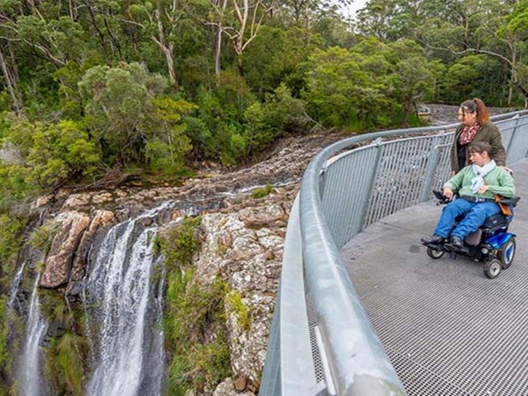 2 visitors to Minyon Falls, one in a wheelchair, look out over the falls from the accessible lookout