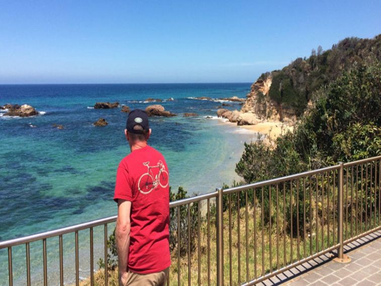 A male tourist enjoys beach and ocean views at Mystery Bay lookout, near Narooma in Eurobodalla