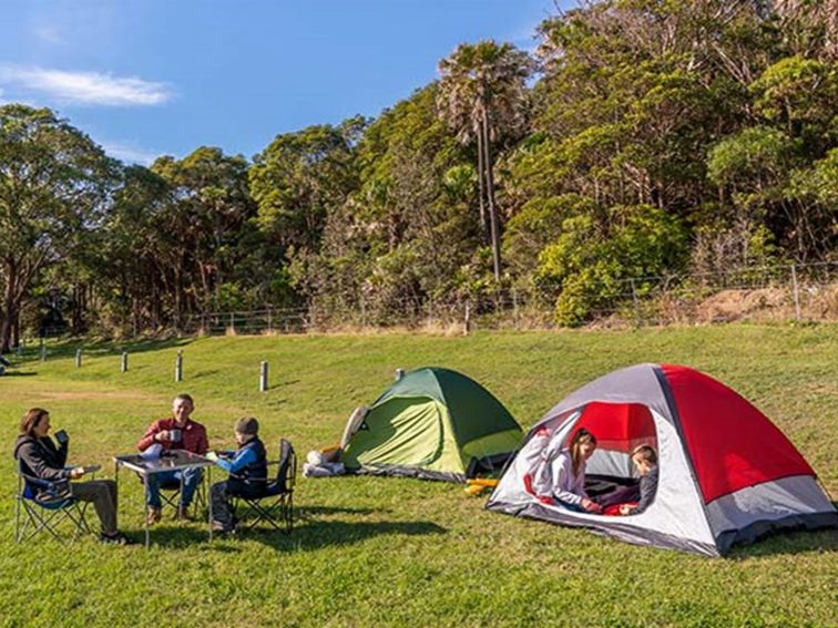 People sitting beside two tents at The Ruins campground in Booti Booti National Park. Photo credit: