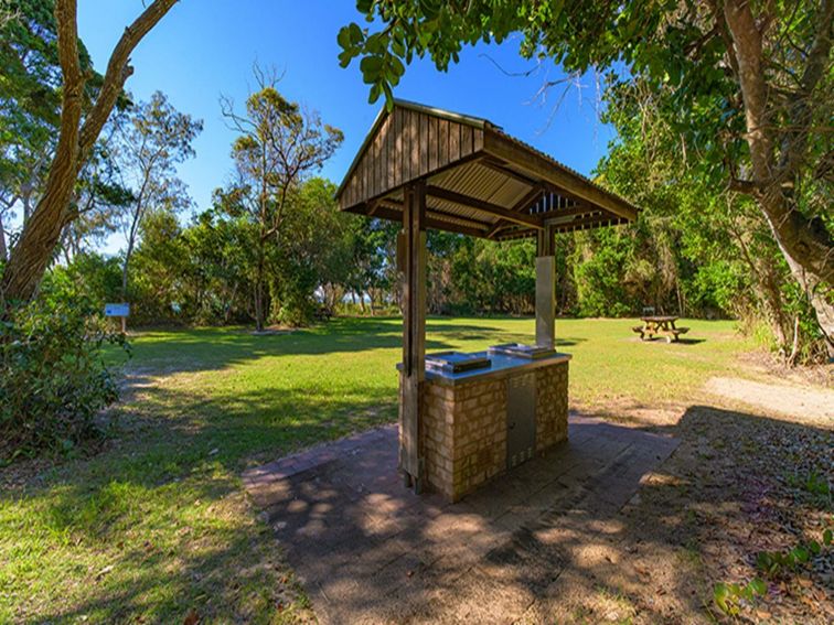 Shark Beach picnic area showing sheltered barbecue, picnic table and grassy area, surrounded by